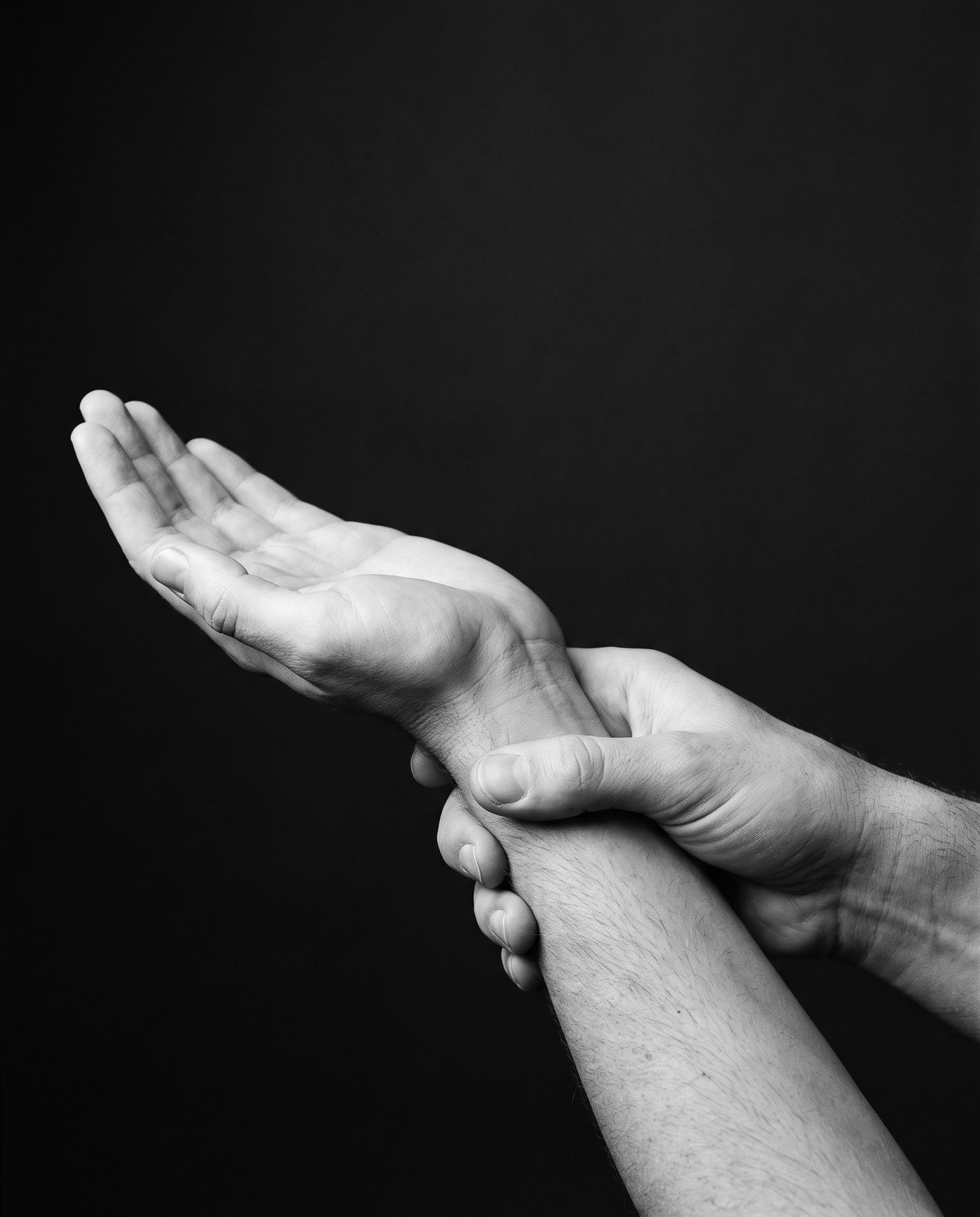 A clinician's hand supporting an adult patient's wrist during a hand and wrist examination.